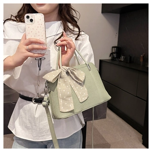 Détail du sac bandoulière tressé vert sauge avec ruban à pois et bandoulière réglable