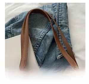 Detailed close-up of premium brown leather tote bag handle with reinforced double stitching