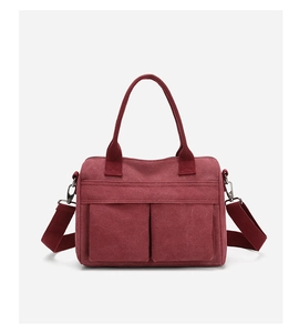 Detail of burgundy canvas tote bag featuring dual front pockets and adjustable strap