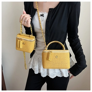 Detail of yellow woven mini box bags with gold camellia logo and metal chain straps