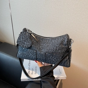 Grande borsa tote leopardata con ciondolo a cuore e borchie su un libro bianco