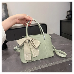 Gros plan du sac à main vert sauge avec un nœud à pois et des détails de texture
