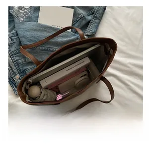 Interior view of brown faux leather tote bag showing large capacity for laptops and books