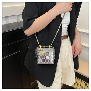 Détail du mini sac bandoulière argenté avec camélia doré et bandoulière chaîne