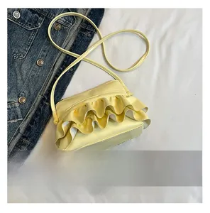 Detailed view of pale yellow pleated crossbody bag with three-layer ruffles on fabric