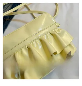 Detailed macro view showing glossy pleated texture and craftsmanship of the yellow bucket bag