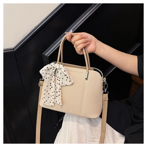 Détail du sac bandoulière tissé beige avec foulard en soie à pois noirs et blancs