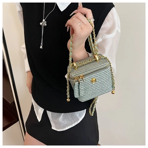 Detail of mint green woven mini box bag with gold camellia clasp and chain strap