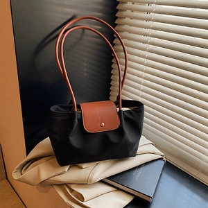 Minimalist black canvas tote bag with brown leather handles and golden button closure