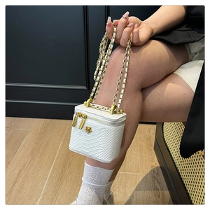 Détail du mini sac blanc à motif crocodile avec logo floral doré et bandoulière chaîne
