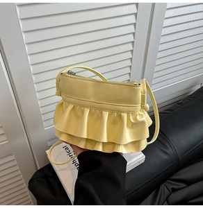 Detail of light yellow ballet style handbag featuring layered leather ruffles and strap