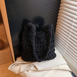 Minimalist black hollow knit tote bag with bohemian crochet pattern on trench coat background