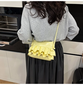 Detail of yellow pleated ruffles on a shiny PU leather crossbody bucket bag