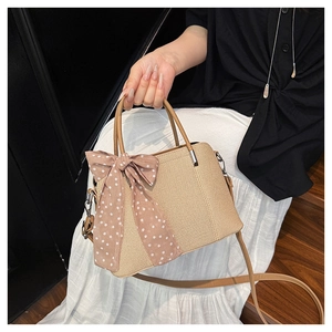Détail d'un sac en paille tissée avec foulard en soie à pois et bandoulière en cuir