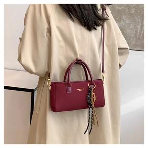 Détail du sac à main carré en cuir mat bordeaux avec breloque étoile et bandoulière réglable