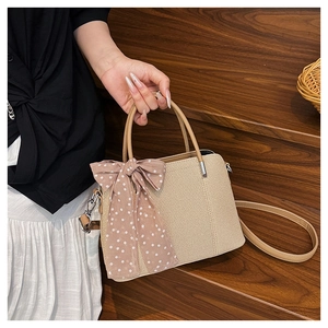 Détail du sac bandoulière en paille tressée avec grand nœud à pois et cuir