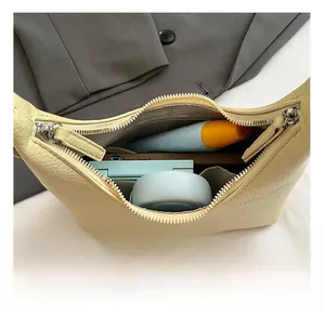 Internal view of a yellow half-moon dumpling bag showing cosmetics and smartphone storage