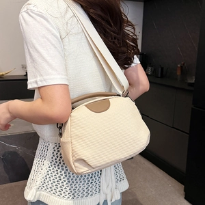 Beige woven crossbody bag with brown leather handles and adjustable shoulder strap