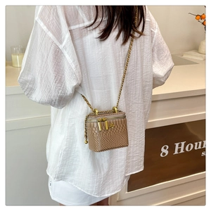 Détail d'un mini sac boîte à relief crocodile avec ornement floral camélia doré