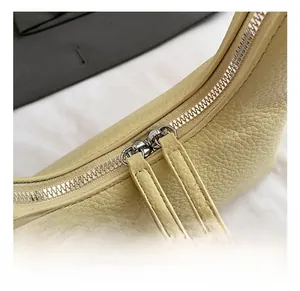 Detail of silver double zippers on yellow pebble leather bag with matching pulls
