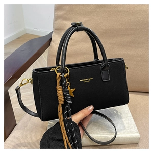 Détail d'un sac à main rectangulaire noir mat avec lettrage doré et étoile