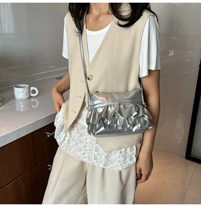 Close-up of metallic silver bucket bag featuring layered ruffle pleats and a slim strap