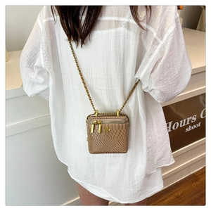 Détail du mini sac bandoulière à motif serpent avec chaîne dorée et emblème floral