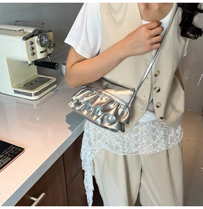 Silver metallic pleated bucket bag with ruffled layers worn as a stylish crossbody bag