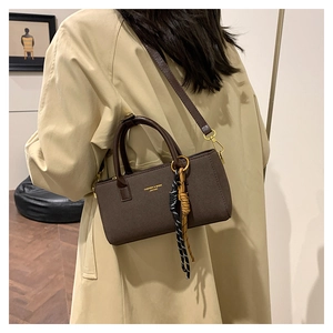 Détail du sac en cuir mat marron foncé avec lettrage doré et accessoire corde tressée