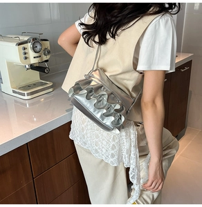 Chic silver metallic bucket bag with ruffle trim shown on model in a modern cafe setting