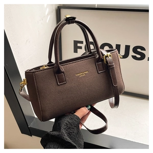 Détail du sac à main marron foncé avec logo doré et bandoulière réglable
