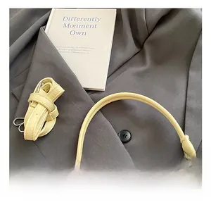 Detail of yellow lychee pattern handbag handle and adjustable strap on a blazer