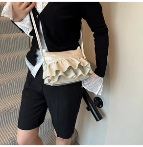 Detail view of the beige ruffled bucket bag with pleated design and smooth leather texture