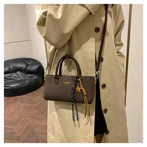 Détail du sac carré marron foncé mat avec pendentif étoile et breloque en corde