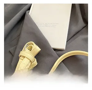 Detail of adjustable litchi texture leather strap with silver metal buckle on a yellow bag