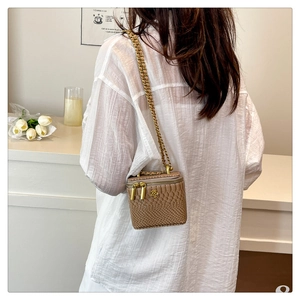 Détail d'un mini sac boîte beige à motif croco avec chaîne dorée et logo fleuri