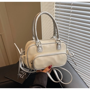 Close-up of beige crossbody bag featuring silver hardware and decorative side ribbons