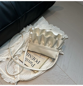 Close-up of ruffled cream bucket bag on vintage French books and textured fabric