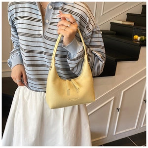 Detail of light yellow lychee pattern leather handbag with embossed fashion logo text