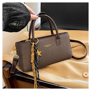 Détail d'un sac à main marron mat avec pendentif étoile et pompon en corde tressée