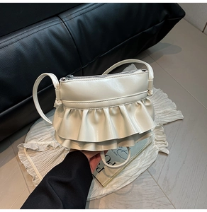 Detail view of cream white bucket bag featuring layered ruffles and smooth leather texture