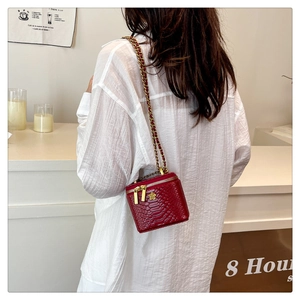Détail du mini sac rouge à chaîne motif crocodile avec fleur dorée