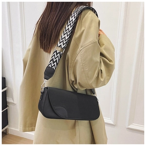 Détail d'un sac bandoulière noir minimaliste avec une large sangle tissée noire et blanche