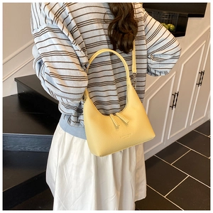 Detail of yellow lychee leather bag with dual zippers and embossed fashion logo