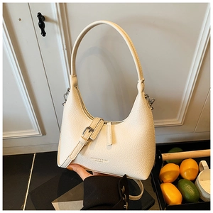 Close-up of cream lychee leather shoulder bag with silver buckle and printed text