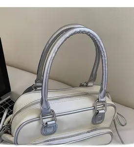 Close-up of the off-white handbag featuring silver metal handles and double zippers