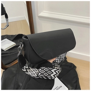 Détail du sac bandoulière en cuir noir mat avec large bandoulière en tissu géométrique
