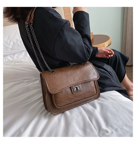 Détail d'un sac à bandoulière matelassé marron avec fermoir argenté et chaîne