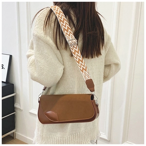 Détail d'un sac à rabat en cuir marron avec patchwork de feuilles et bandoulière tissée