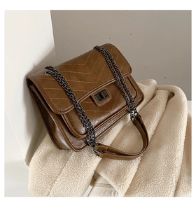 Gros plan du sac en cuir marron avec surpiqûres en V et bandoulière chaîne en métal